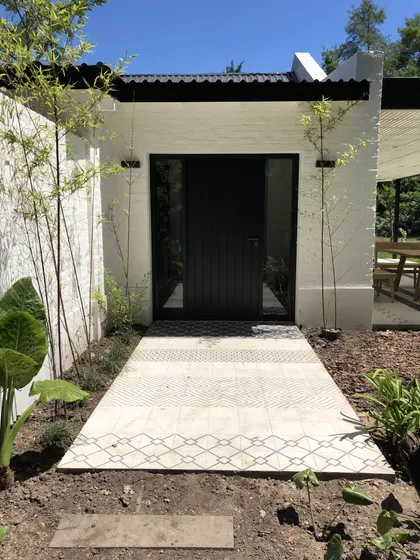 entrada moderna con puerta corrediza de madera y sendero de baldosas — proyecto Casa BA, por Estudio Dado, en Pilar
