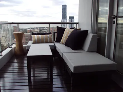 Balcón moderno con sofá seccional gris y vista urbana — proyecto Torre Bellini, por Estudio G, en CABA