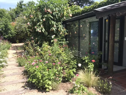 Fachada moderna de casa con jardín exuberante y sendero de madera — proyecto Monroe - La Horqueta, por Mgc.arq, en La Horqueta