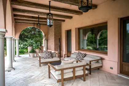 Galería cubierta con arcos, columnas y muebles de madera natural — proyecto CasaLA, por Ricardo Pereyra Iraola 