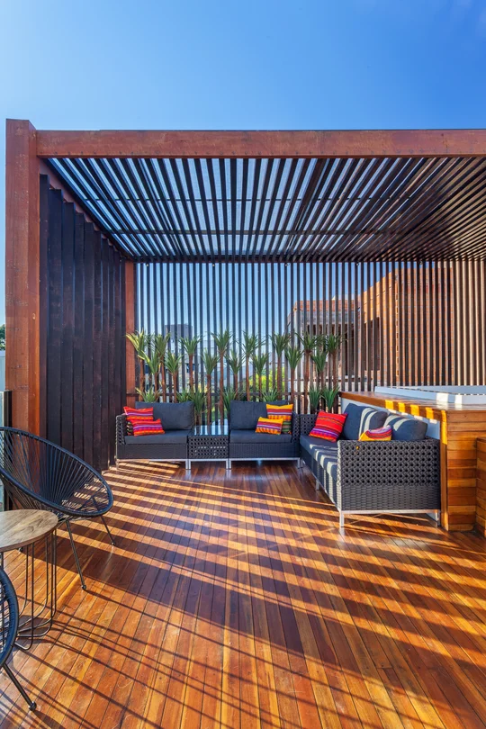 Terraza con pergola de madera, deck rayado y mobiliario moderno — proyecto CASA RR, por Frederico Bicalho Arquitetura