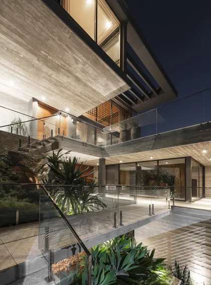 Terraza moderna nocturna con plantas, escaleras y vidrio estructural — proyecto Casa M.T., por Ruschel Arquitetura e Urbanism