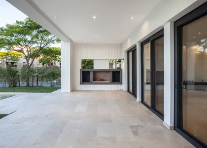 Patio moderno con hogar, grandes ventanales y jardín luminoso — proyecto El Golf 137 - Nordelta, por Build a Home Arquitectura, en B1624 Tigre