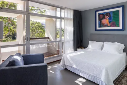 Dormitorio moderno con cama blanca y vista al balcon con jardin vertical — proyecto Apartamento 312S, por Coda Arquitetos