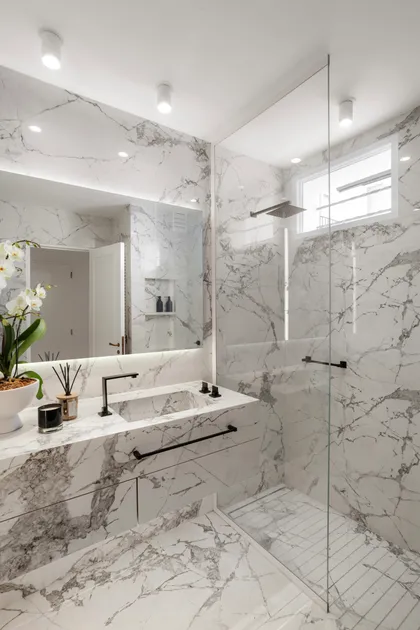 baño moderno con revestimiento de mármol, grifería negra y ducha de cristal — proyecto Alvear | Redefining luxury, por Ren Studio, en Recoleta