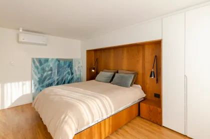 Dormitorio moderno con paneles de madera y cama amplia — proyecto Guayra - Andrea Gonzales, por ABEJA CONCEPT, en Belgrano