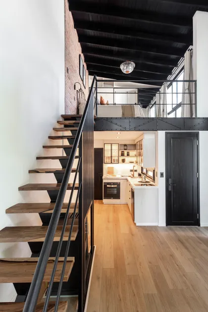 Loft industrial con escalera flotante y cocina blanca — proyecto JURAMENTO, por Nima Estudio, en Buenos Aires