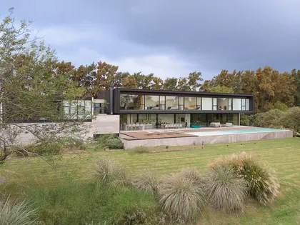 Fachada moderna de hormigón con piscina y ventanas de piso a techo — proyecto PG.A, por Casa Cunia, en Buenos Aires
