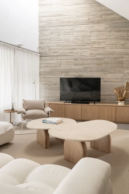Living moderno con pared de piedra texturizada y mesas de madera orgánicas — proyecto PROYECTO NAUDIR, por July Acosta Home, en Belén de Escobar
