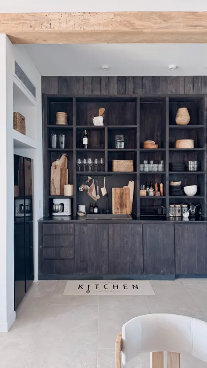 Cocina rústica moderna con estanterías de madera oscura y vigas expuestas — proyecto El Refugio, por Grupo Pauta Arquitectura, en Pinamar