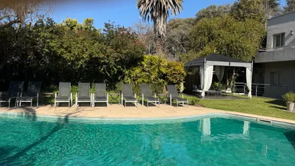 Área de piscina residencial moderna con deck de madera y vegetación exuberante — proyecto Villa Isidro Hotel Boutique & Spa, por Hermann Arquitectos, en San Isidro