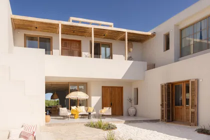 Patio mediterráneo con muebles de rattan y vigas de madera — proyecto El Refugio, por Grupo Pauta Arquitectura, en Pinamar