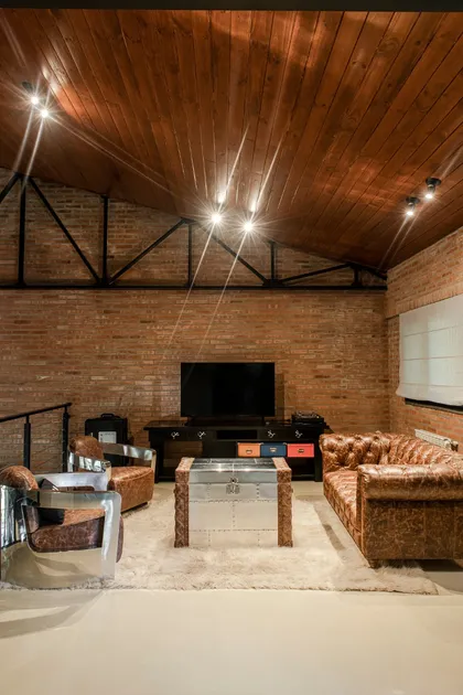 Sala de estar industrial con sofás de cuero marrón y sillas aviador — proyecto Loft y garage autos de colección , por Arq. Damian Fainzilber, en San Isidro