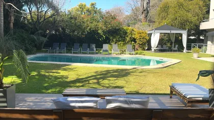 Amplia piscina moderna con área de descanso y jardín frondoso — proyecto Villa Isidro Hotel Boutique & Spa, por Hermann Arquitectos, en San Isidro