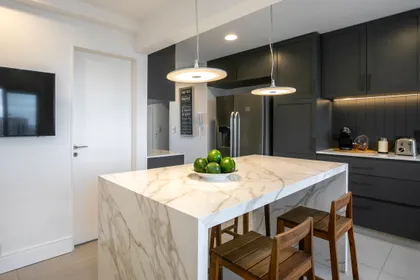 Cocina moderna con isla de mármol y gabinetes oscuros — proyecto Obra Araoz A, por Arq. Lourdes Yarade Saravia, en Buenos Aires