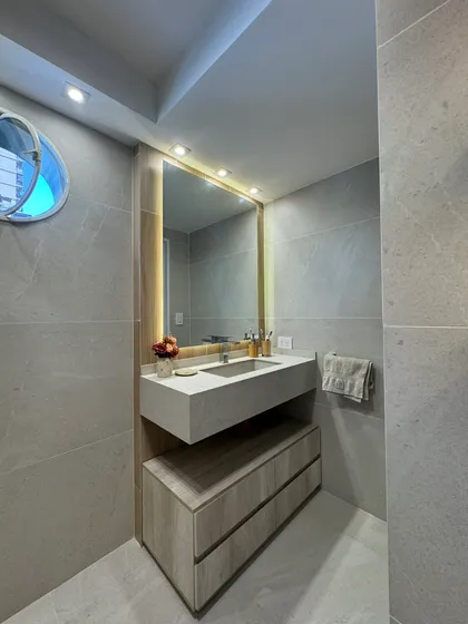 Baño moderno con vanitory flotante, espejo grande retroiluminado y revestimiento de piedra — proyecto Bulnes, por MDBK Arquitectura, en Palermo