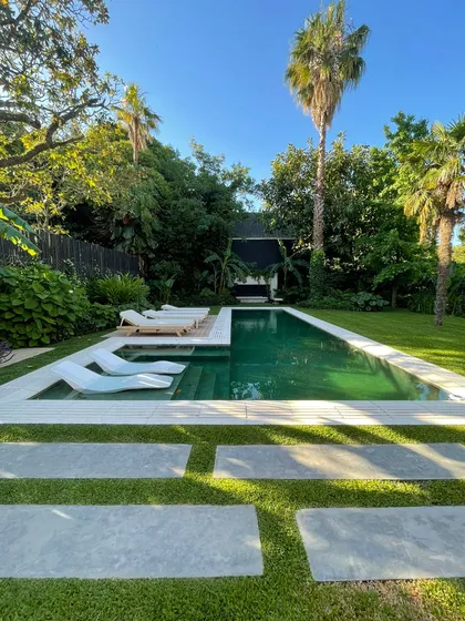 Piscina moderna rodeada de vegetación tropical y deck de hormigón — proyecto Ladislao_EA, por Eugenia Anaya -estudio de paisajismo-, en B1641 Acassuso