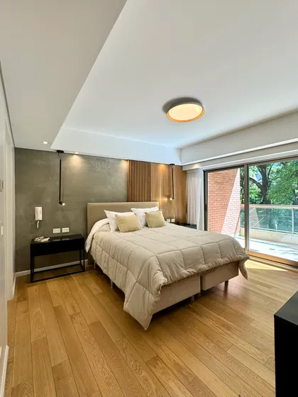 Dormitorio moderno con cama grande, suelo de madera y luz indirecta — proyecto Olleros, por MDBK Arquitectura, en Belgrano