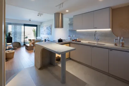 Cocina moderna abierta con isla curva de hormigón y cascada — proyecto Satori, por KUPERDESIGN CONSTRUCCIONES SRL, en Buenos Aires