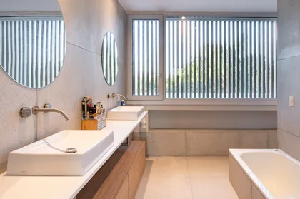 baño moderno con espejos redondos y ventana con lamas — proyecto Campo grande I, por Juarez-Fevre Estudio de Arquitectura , en Pilar