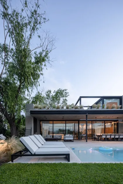 Casa moderna con pileta y sillones blancos, techo verde — proyecto CASA AWA, por radovic_arquitecto, en Benavidez