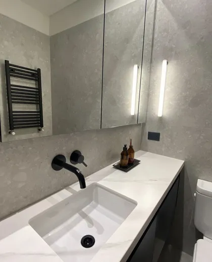 Baño moderno con revestimiento gris, mesada de mármol y grifería negra — proyecto Baños Belgrano, por Cudini Estudio, en Belgrano