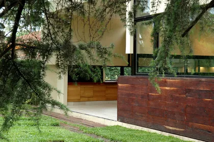 Fachada contemporánea con madera y vidrio rodeada de enredadera — proyecto Casa en Pilar, por Luciano Kruk, en Pilar