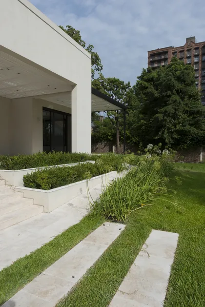 Fachada moderna con jardineras integradas y caminos de piedra — proyecto Casa C, por Estudio Dado, en Belgrano