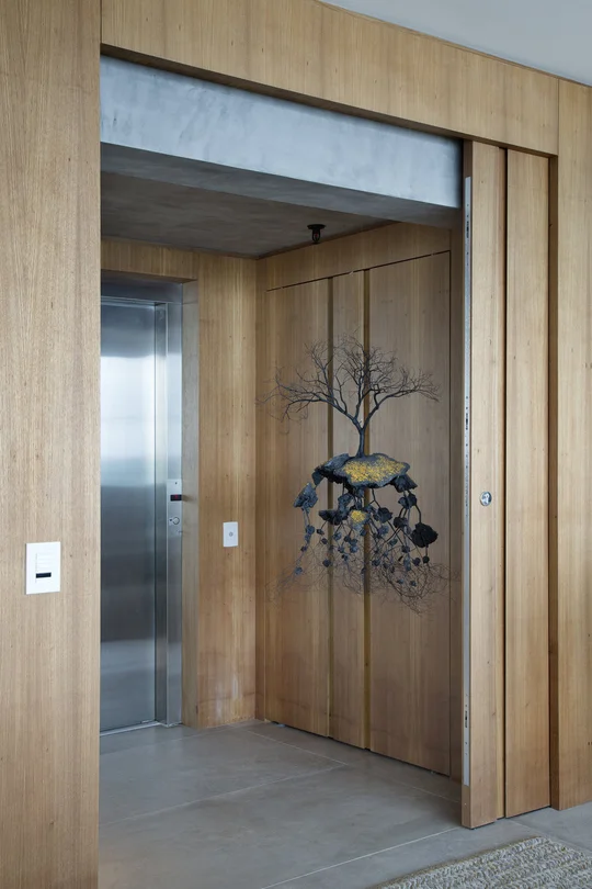 Pasillo moderno con ascensor y puerta de madera, instalación artística árbol — proyecto PL House, por Studio Ro-ca