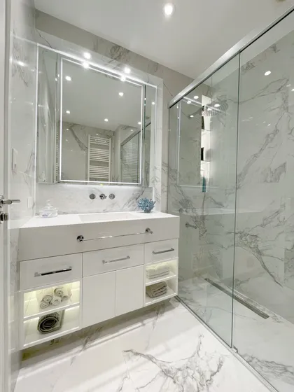 Baño moderno con mármol, espejo iluminado y ducha de vidrio — proyecto Remodelación Baño, por Estudio Nicolás Pierry