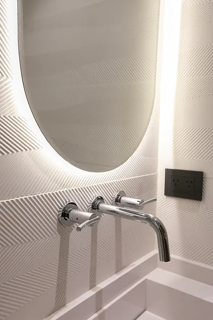 Baño minimalista blanco con espejo oval iluminado y grifería cromada — proyecto Casa Oroño, por Estudio Plats, en Buenos Aires