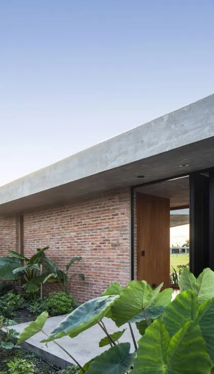 Fachada moderna con ladrillo expuesto y gran alero de hormigón — proyecto Casa Volt, por Estudio PK, en Capilla del Señor