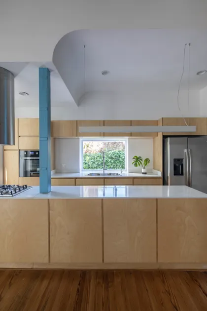 Cocina moderna con isla central, columna azul y techo curvo — proyecto Reforma Alsina, por Estudio YME, en San Isidro