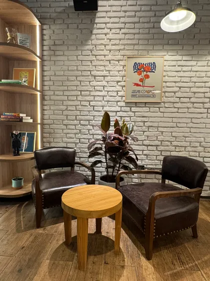 Sala de estar industrial con ladrillo expuesto y sillones de cuero — proyecto zarpado café , por Remodela tu local , en Martínez