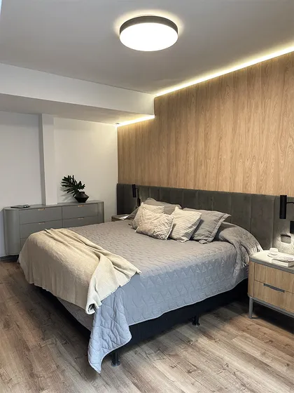 dormitorio moderno con cama tapizada y pared de madera natural — proyecto Casa Oroño, por Estudio Plats, en Buenos Aires