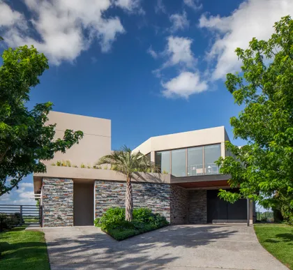 fachada moderna de piedra y hormigón con vegetación exuberante — proyecto CASA M40, por A'PRIMA - Arquitectura Sustentable, en Unnamed Road