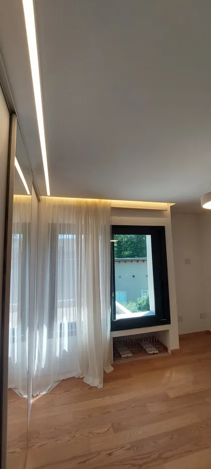 Living moderno con piso de madera y luz indirecta en el techo — proyecto Casa eterna, por Plasma co, en Canning
