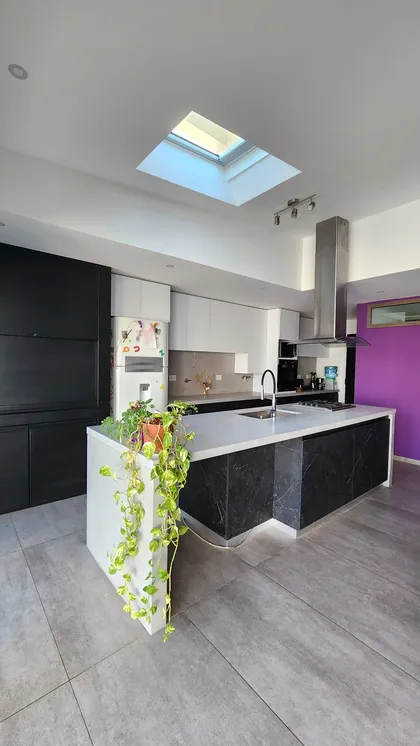 Cocina moderna con isla, luz cenital y pared violeta — proyecto Casa Berner, por Zima Arquitectura, en La Plata