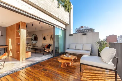Terraza moderna con deck de madera y sillones blancos — proyecto Depto Valle, por Ayelen Mayer Arquitectura, en Buenos Aires