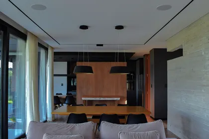 Comedor moderno con mesa de madera y luces cónicas colgantes — proyecto CASA HC, por Daniel Daniele - Oficina de Arquitectura, en Canning