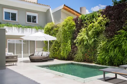 Living moderno exterior con piscina y pared verde exuberante — proyecto Residência Jardim Lusitânia, por Almada Arquitetura, en São Paulo