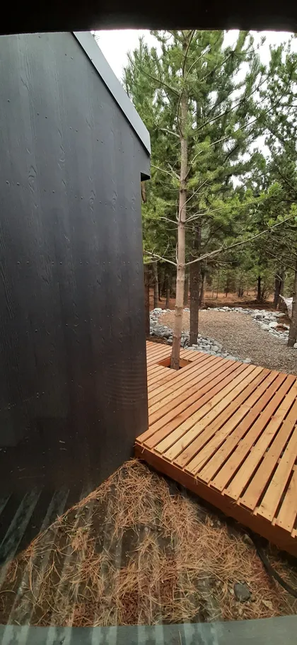 fachada negra moderna con deck de madera y bosque — proyecto Casa LA MOROCHA, por Showhouse Bariloche, en San Carlos de Bariloche