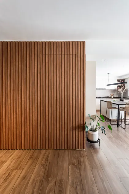 Living moderno con pared de listones de madera y cocina integrada — proyecto Casa en Martinez, por JT ARQUITECTURA, en Martínez