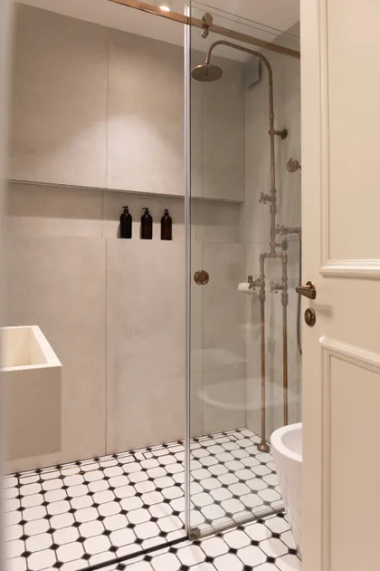 Baño con ducha de latón, paredes de piedra y suelo ajedrezado — proyecto LIBERTADOR DANDY, por AB ARQUITECTURA, en Recoleta