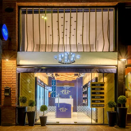 Fachada nocturna de local comercial con vidrieras y plantas decorativas — proyecto PEZ, Almacén de Congelados - Arquitectura Comercial, por Síncresis Arquitectos, en Ciudad de Córd