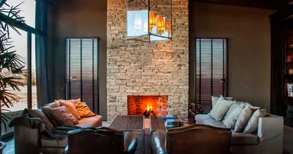 Living con hogar central, ladrillo visto y sillones frente a fuego — proyecto El Sum, por El Naudir