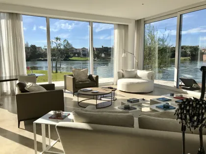 Living moderno con vista al agua y muebles curvos — proyecto CASA LAGUNA, por Estudio Xime Fontan Balestra, en Tigre