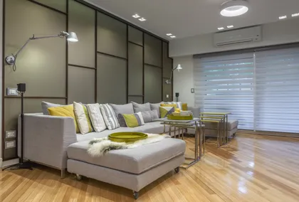 Living moderno con sofá seccional gris y pared de paneles — proyecto Piso en Belgrano III, por Gutman+Lehrer Arquitectas, en Belgrano