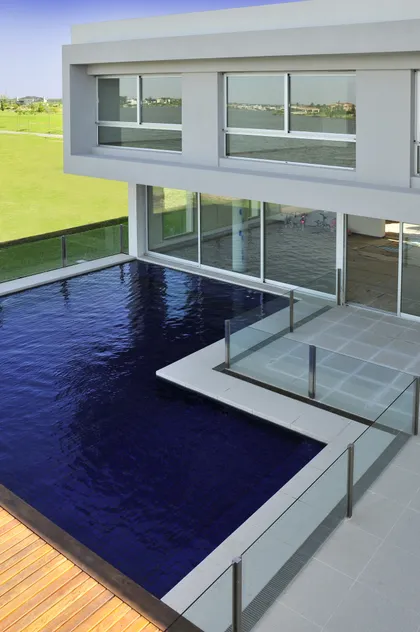 Moderna casa con piscina azul profundo y deck de madera — proyecto Agua & Glamour, por Apaarquitectura, en Zona norte provincia buenos aires