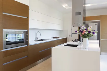 Cocina moderna con isla blanca, madera clara y electrodomésticos integrados — proyecto Modernismo Náutico, por Apaarquitectura, en Tigre